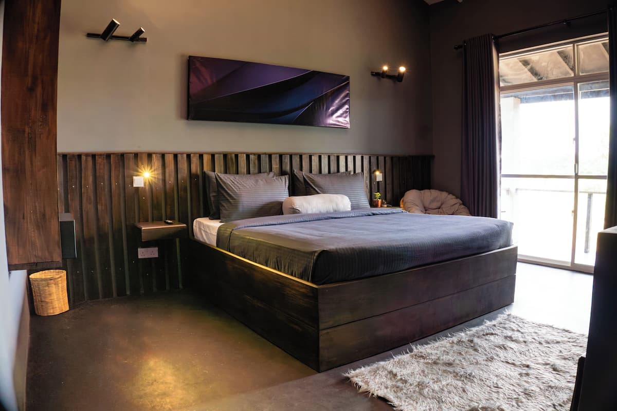 Un dormitorio moderno con una cama grande, cabecera de madera y un ventanal con cortinas.