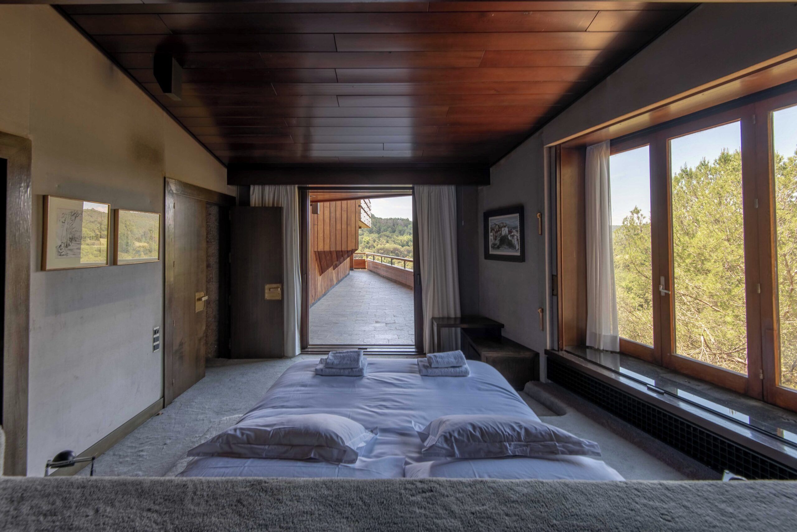 Une chambre avec un grand lit, un plafond en bois et une vue sur un balcon.