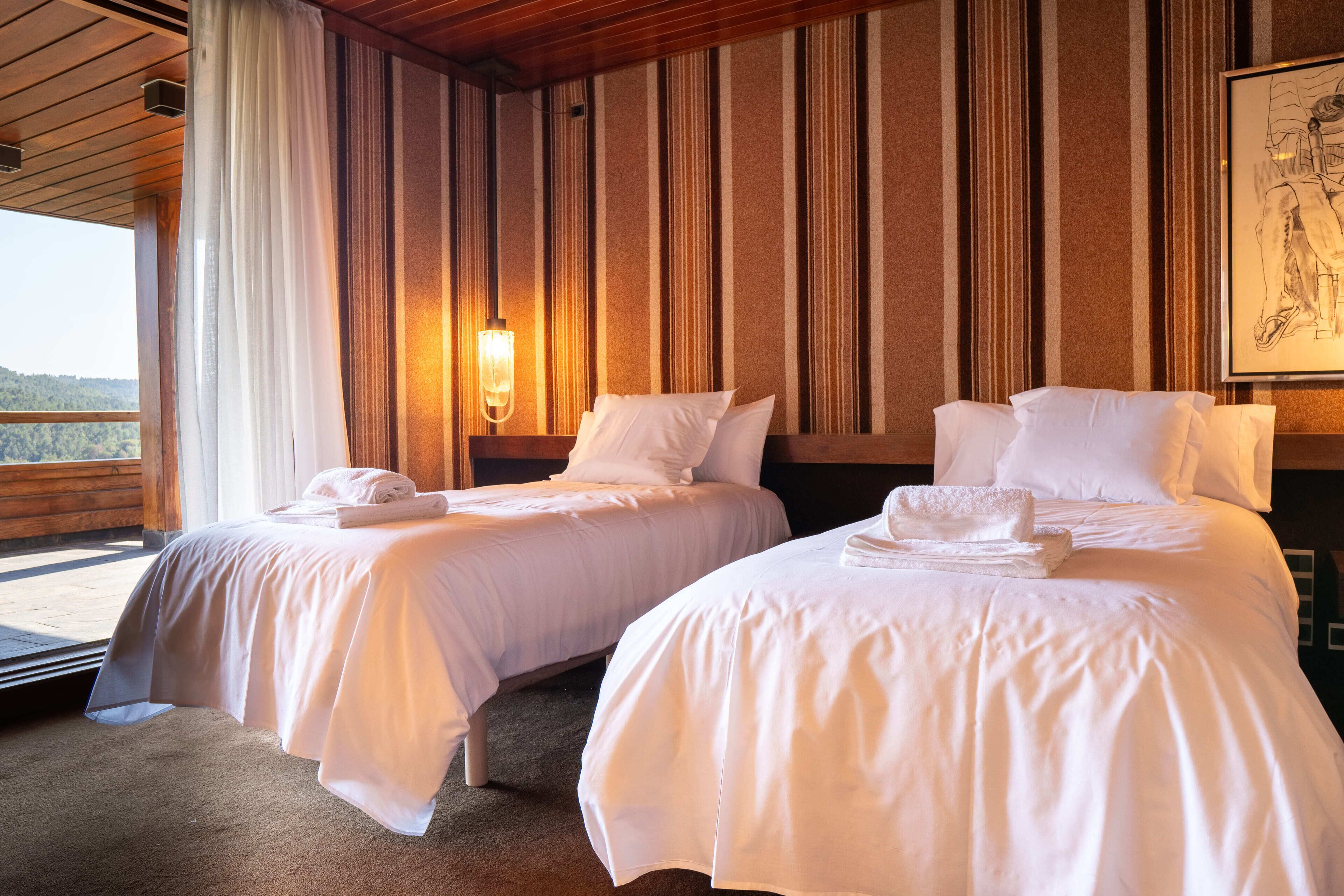 Une chambre d’hôtel avec deux lits, une grande fenêtre et une vue sur l’extérieur.