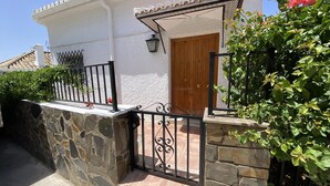 A house with a stone wall, a wooden door, and a black metal gate.