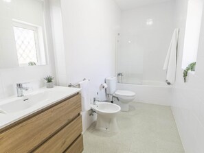 Een moderne badkamer met een houten wastafel, toilet, douchetoilet en bad.