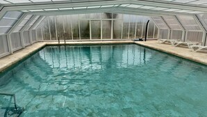 A clear indoor swimming pool with a glass ceiling, surrounded by a white poolside area with lounge chairs. - PINTADO, 5 Bedroom House in Complejo Rural Orgiva (Orgiva)