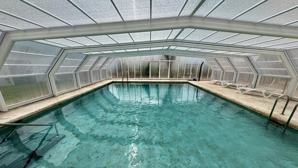 A swimming pool with a glass ceiling, clear water, and white lounge chairs along the edge. - GUADAIRA, 4 Bedroom House in Complejo Rural Orgiva (Orgiva)
