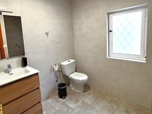 Ein Badezimmer mit Toilette, Waschbecken und einem Fenster.