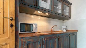 A kitchen with a microwave, coffee maker, and teal cabinets. - Borgo al Sole 2 by Wonderful Italy (Puegnago del Garda)