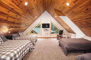 Une chambre avec deux lits, une télévision et un plafond en bois.