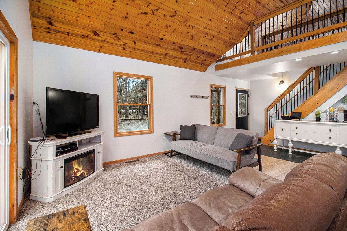 Ein Wohnzimmer mit Kamin, Fernseher, Sofa und einer Treppe.