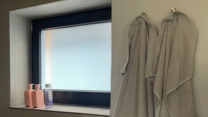 Une salle de bain avec une fenêtre, un porte-serviettes et des articles de toilette sur le comptoir.