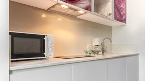 Eine moderne Küche mit eingebauter Mikrowelle, einer Kaffeemaschine und einem Glasbehälter auf der Arbeitsplatte.