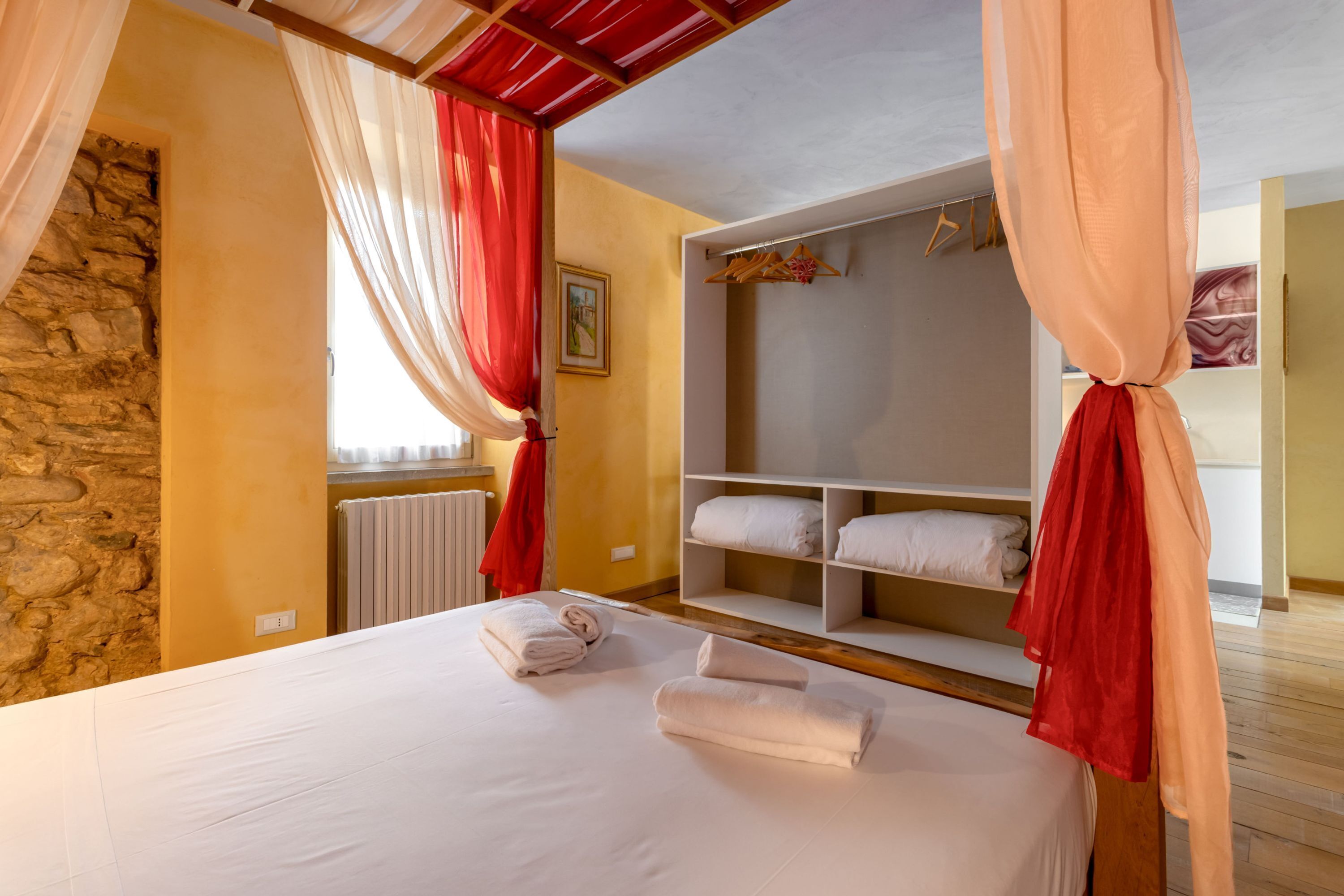 Une chambre à coucher avec un lit, une armoire blanche et un mur en pierre.