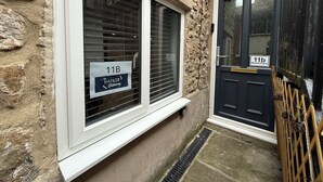 A stone building with a black door and a window with a sign reading "11B The Market Hideaway." - The Market Hideaway - Bedale town centre (Bedale)