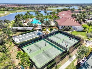 Complejo de canchas de tenis con varias canchas, piscina y zonas verdes circundantes.