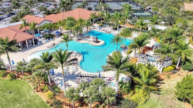 Un complexe hôtelier doté d’une piscine centrale, de palmiers et offrant une vue sur le paysage environnant.