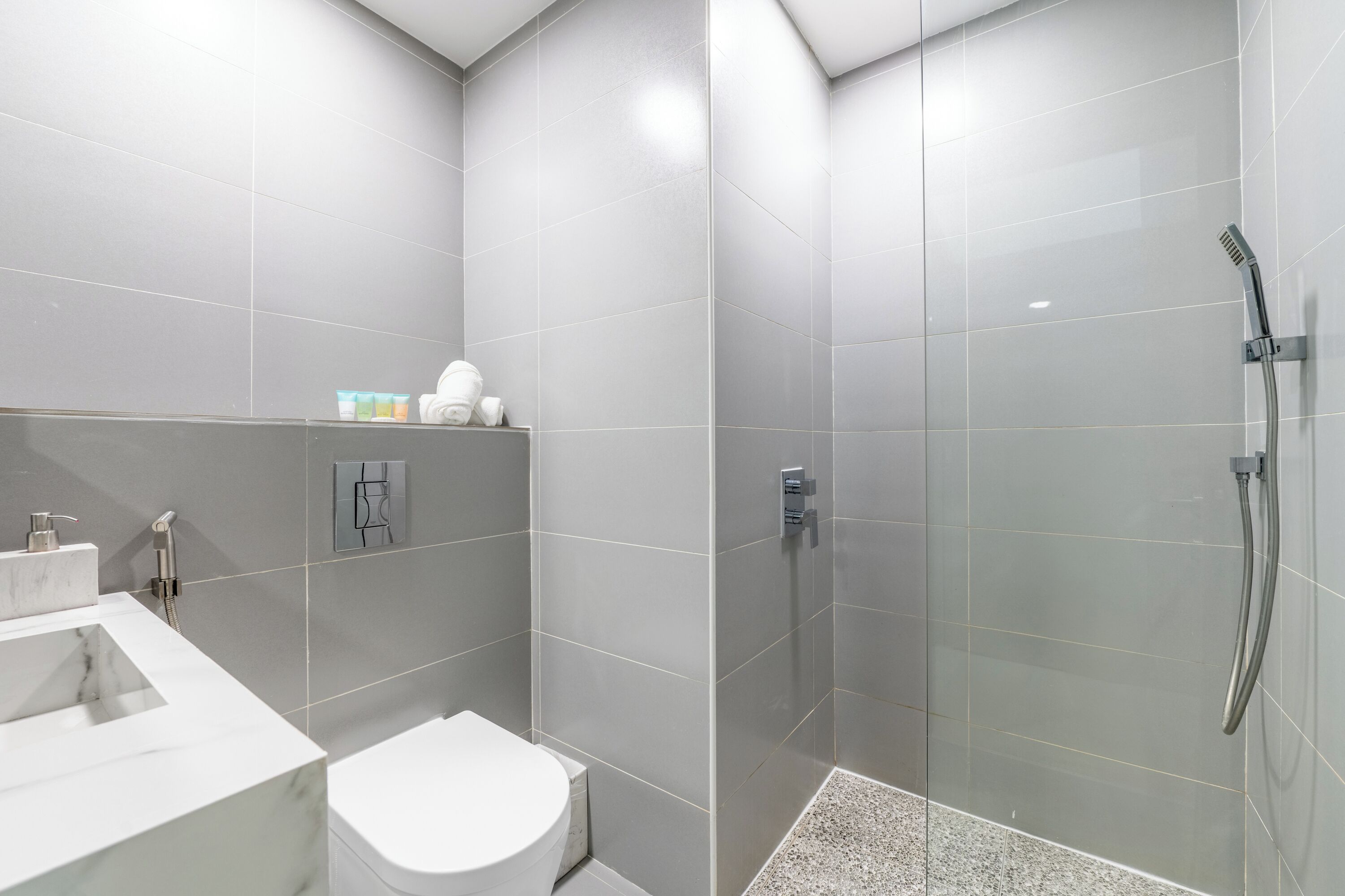 A modern bathroom with a glass-enclosed shower, a white toilet, and a marble sink.