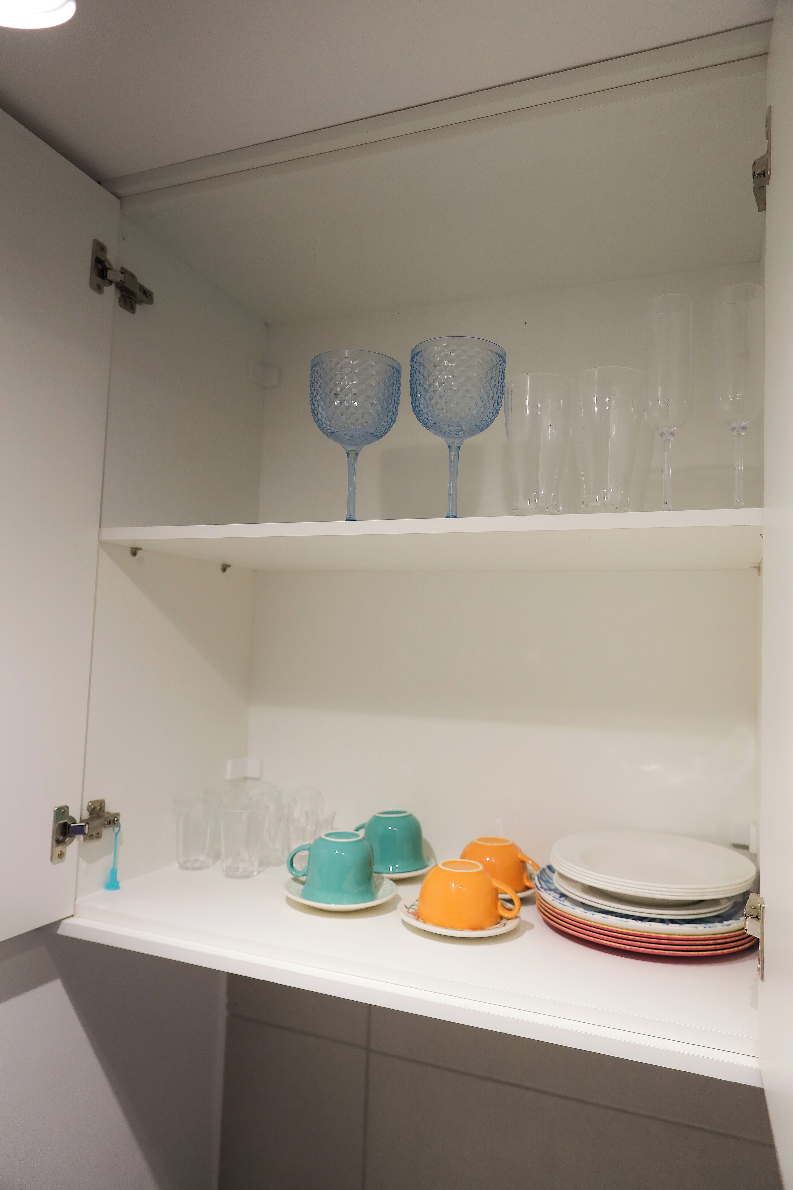 A white shelf with glassware and dishes.