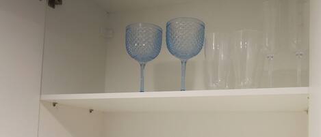 A white shelf with glassware and dishes.