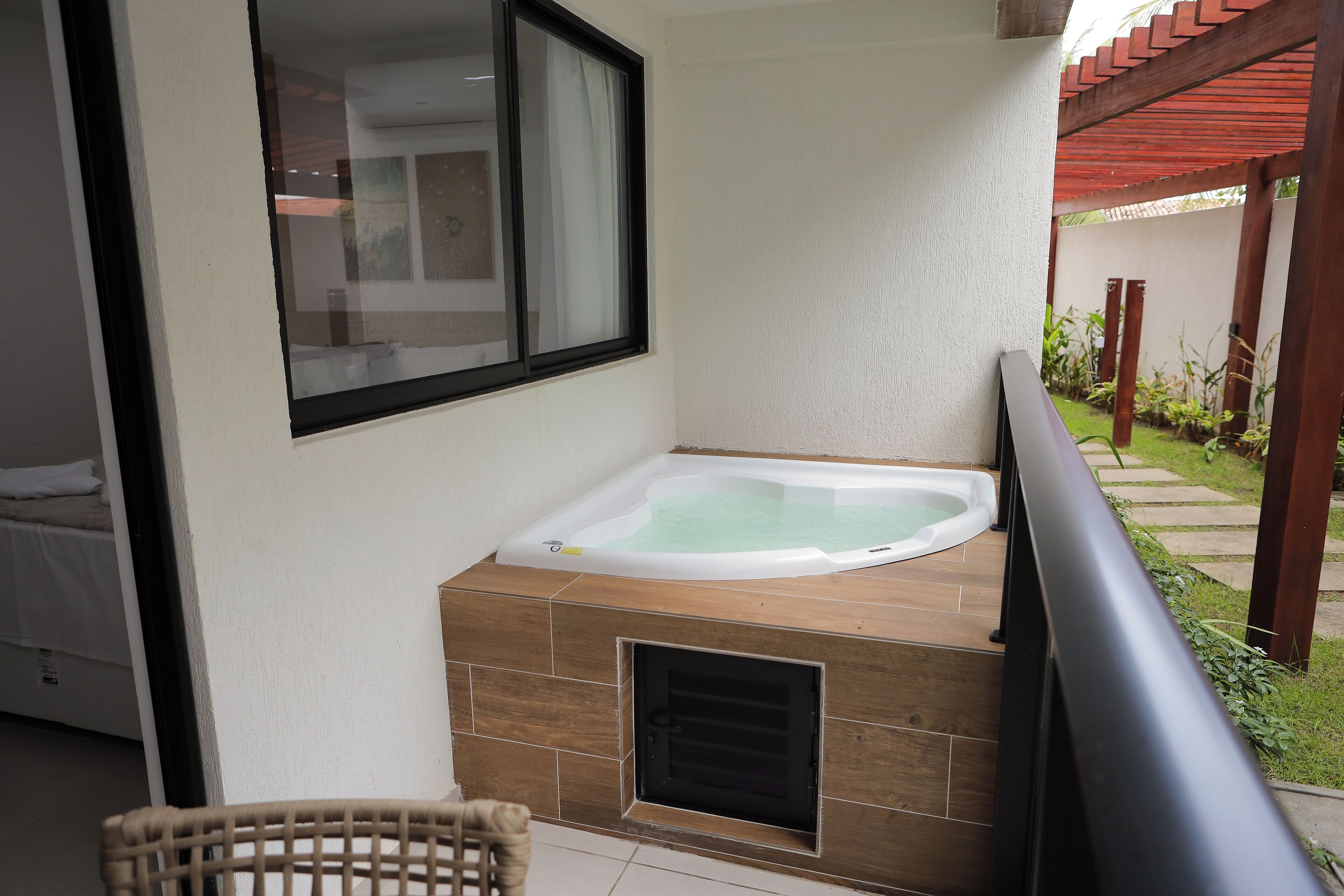 A bathroom with a bathtub, a window, and a view of a garden.