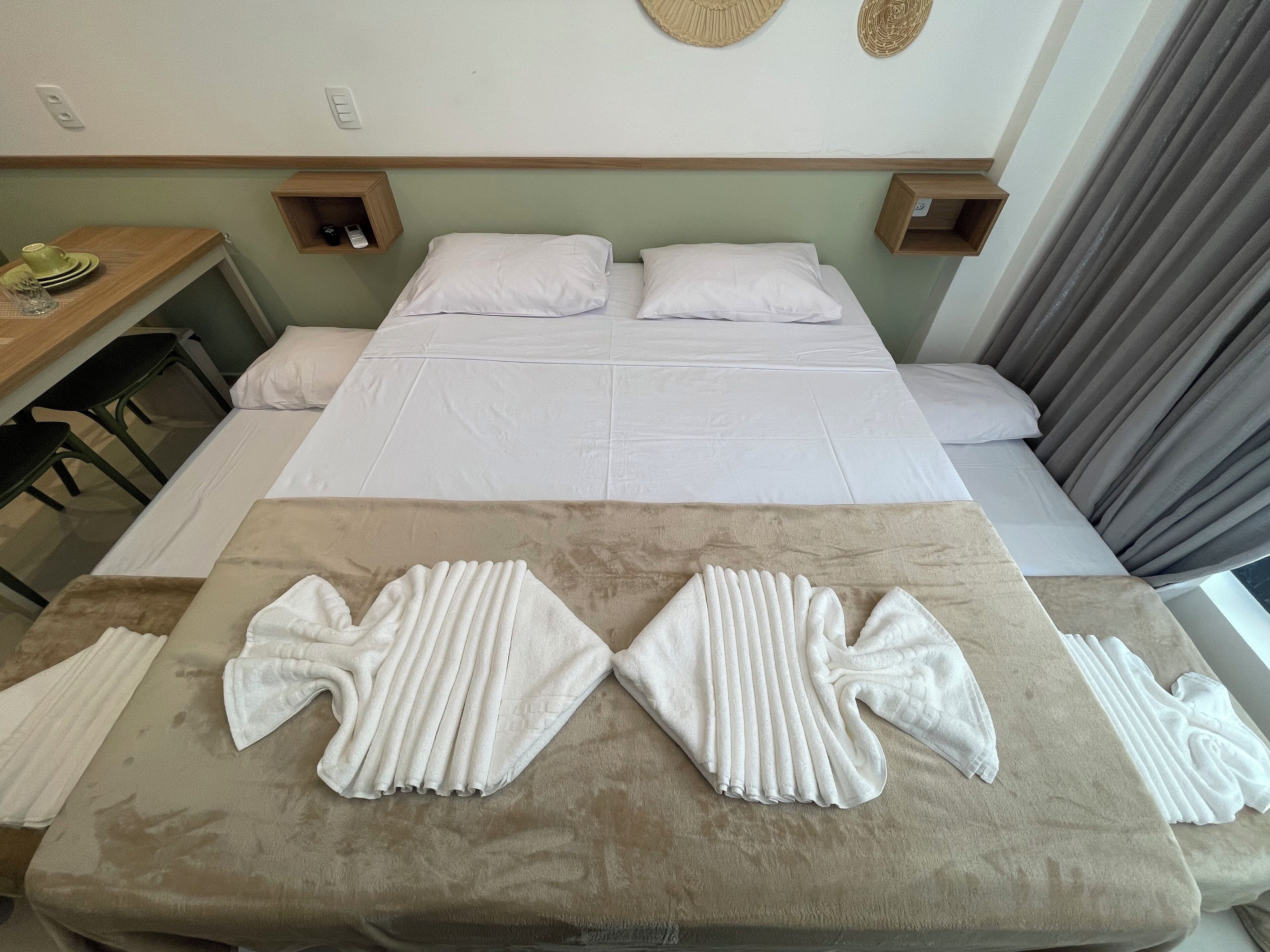Une chambre d’hôtel avec un grand lit, deux tables de chevet, un bureau en bois et un coin salon avec des serviettes.