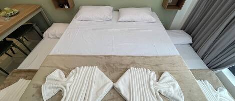 A hotel room with a large bed, two bedside tables, a wooden desk, and a seating area with towels.