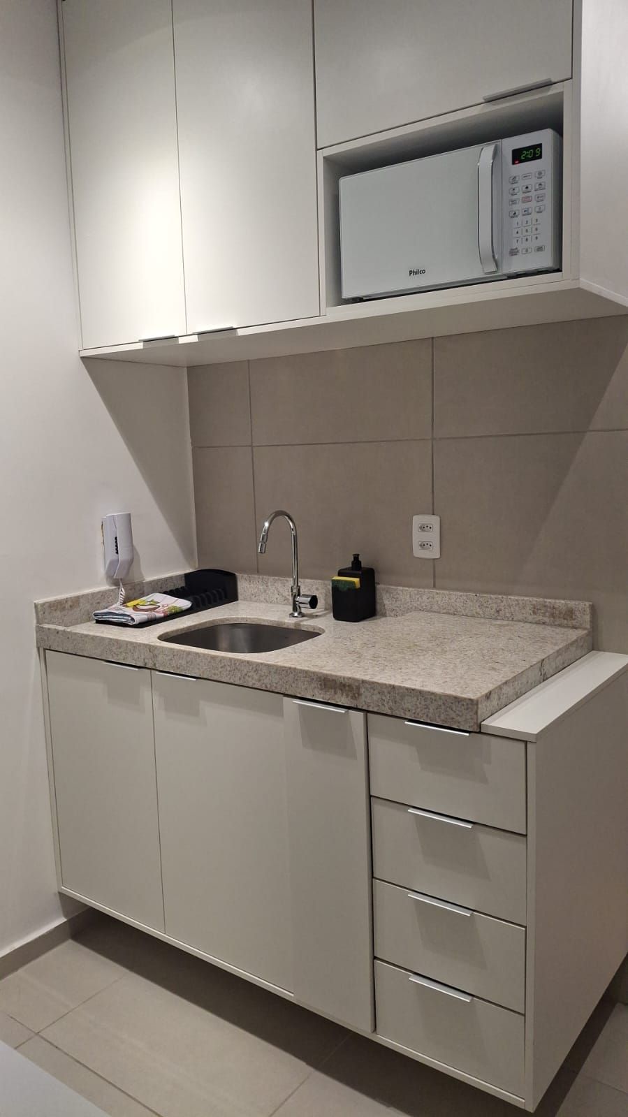 A modern kitchen with a built-in microwave, a sink, and a countertop.