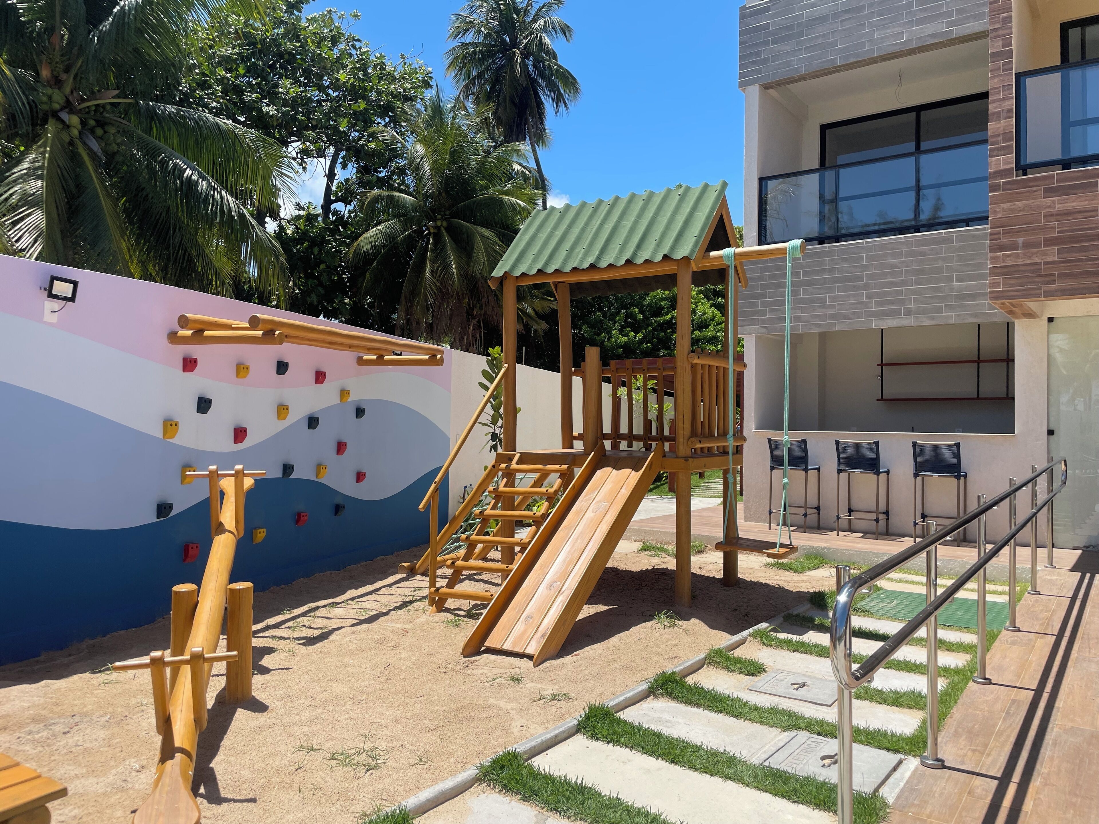 A playground with climbing walls, a slide, and a wooden structure.