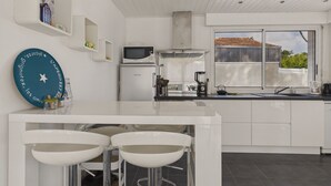 Uma cozinha moderna com armários brancos, micro-ondas embutido e uma janela grande com vista para o exterior.