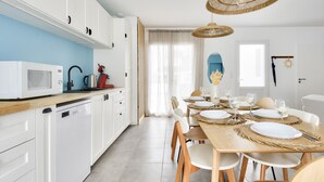 Une cuisine moderne avec des meubles blancs, un four à micro-ondes et une bouilloire posés sur le plan de travail.