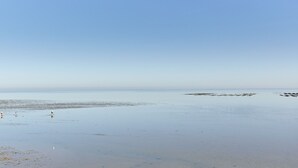 Platja ampla i oberta amb aigües tranquil·les i un cel serè.