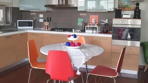 Une cuisine moderne avec des meubles en bois, un four à micro-ondes, une cuisinière et une table à manger avec des chaises rouges.