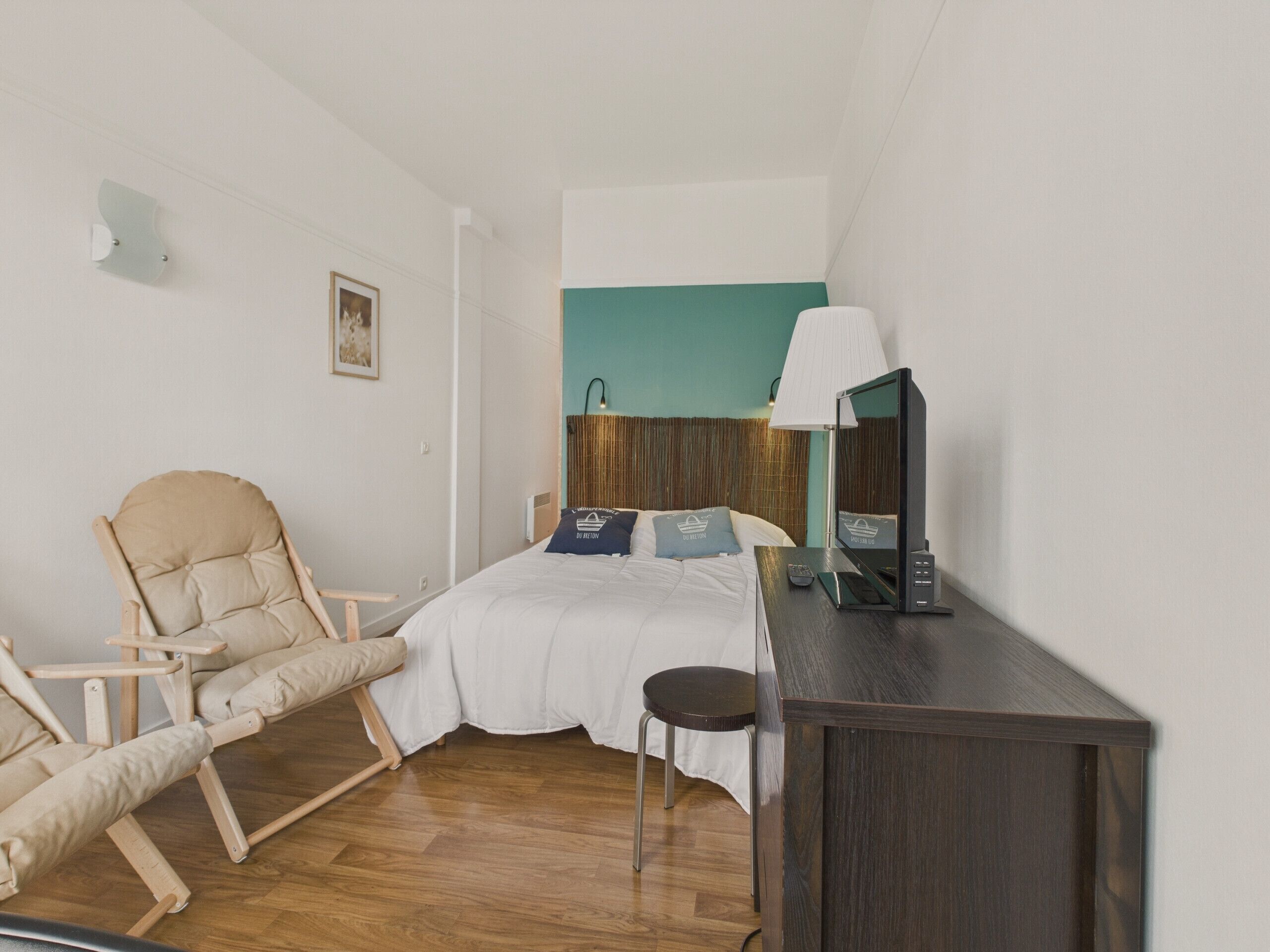 A bedroom with a bed, a chair, a desk, and a lamp.