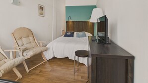 Un dormitorio con una cama, una silla, un escritorio y una lámpara.