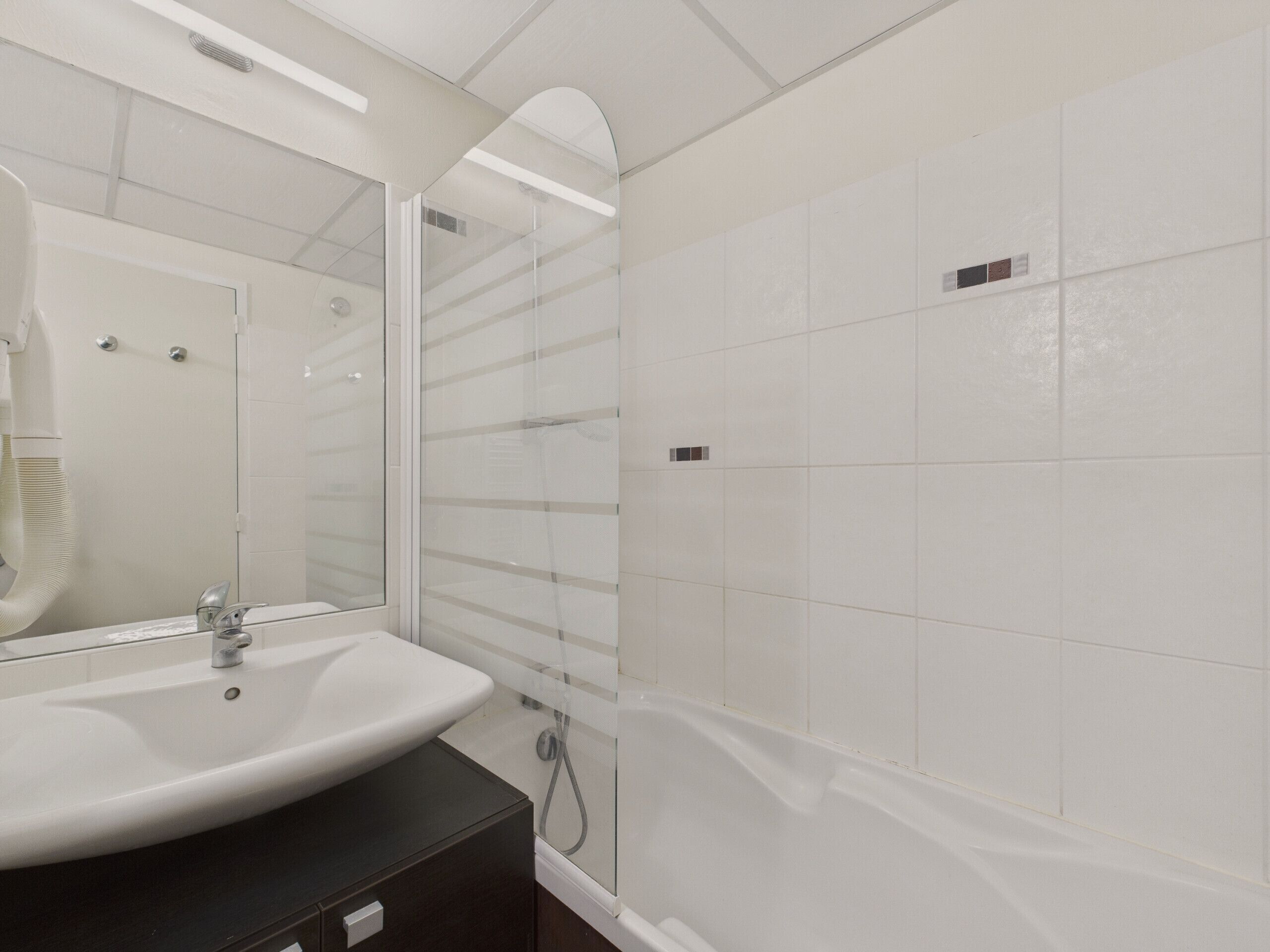A bathroom with a white sink, a mirror, and a glass shower enclosure.
