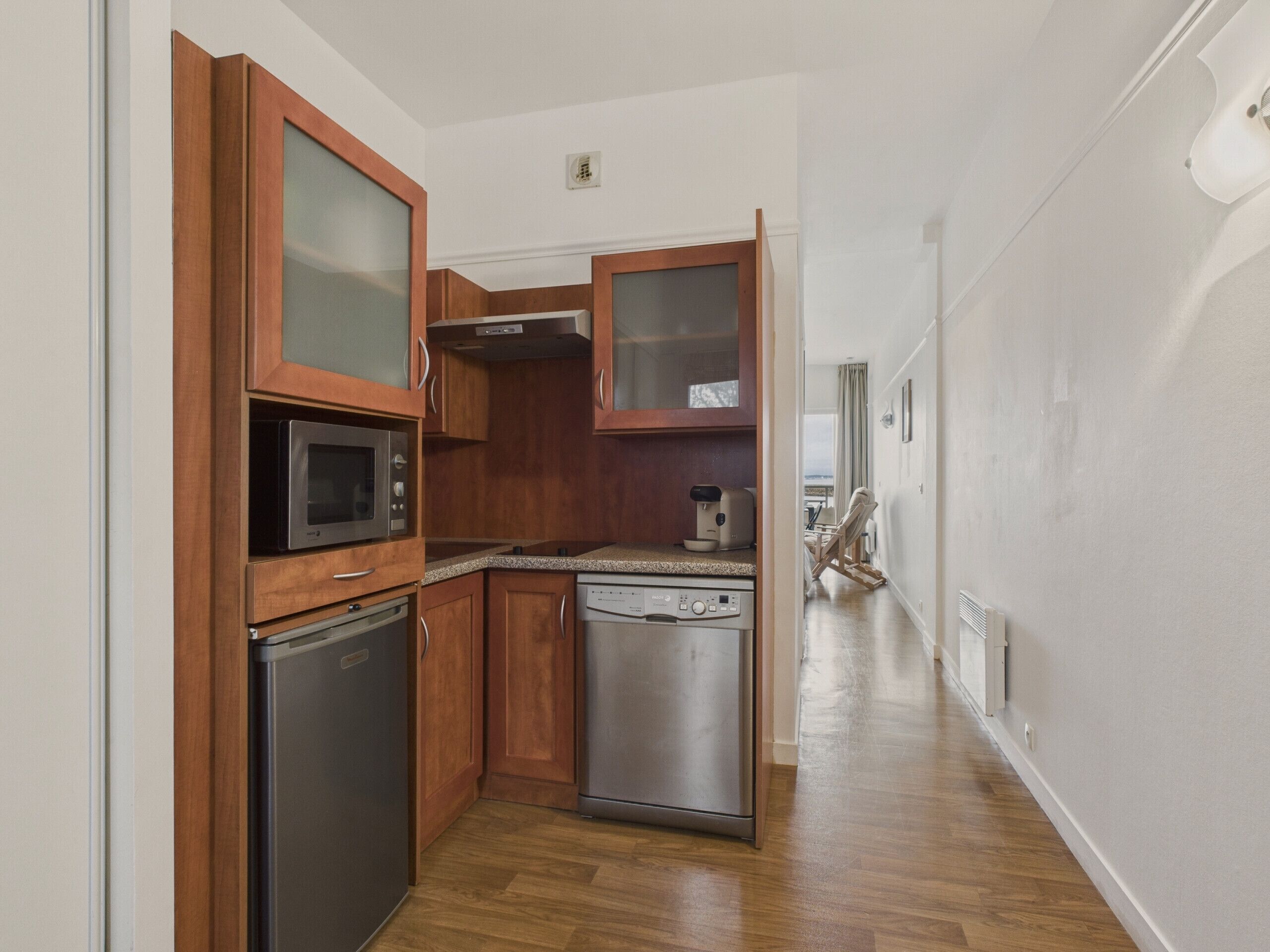 A compact kitchen with wooden cabinets, a microwave, a dishwasher, and a coffee maker.