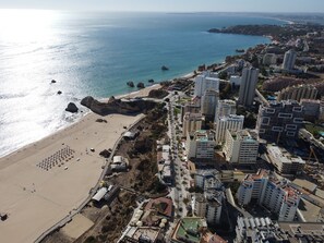 Une vue aérienne d’une ville côtière, avec une plage, des immeubles de grande hauteur et une vue dégagée sur la mer.