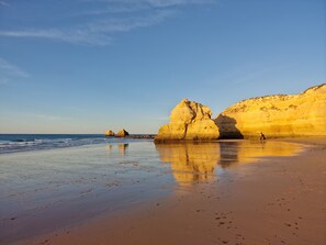 A beach with large rock formations and a clear sky.