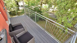 Ein Balkon mit Korbmöbeln und Metallgeländer.