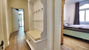Ein Schlafzimmer mit einem Bett, einer hölzernen Bank und einer Tür zu einem anderen Raum.