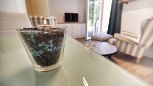 Ein Glas mit Schokoladenstückchen auf einem Tisch in einem Raum mit Fernseher, Sofa und gestreiftem Stuhl.