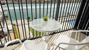 A balcony with a glass table and two white chairs, overlooking a body of water. - Yas Island Waters Edge Studio (Abu Dhabi)