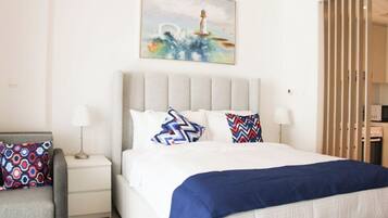 A bedroom with a bed, two bedside tables, a chair, a painting, and a wardrobe.