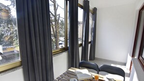 A balcony with a table set for two, featuring a book, a glass of orange juice, and a plate of cookies.