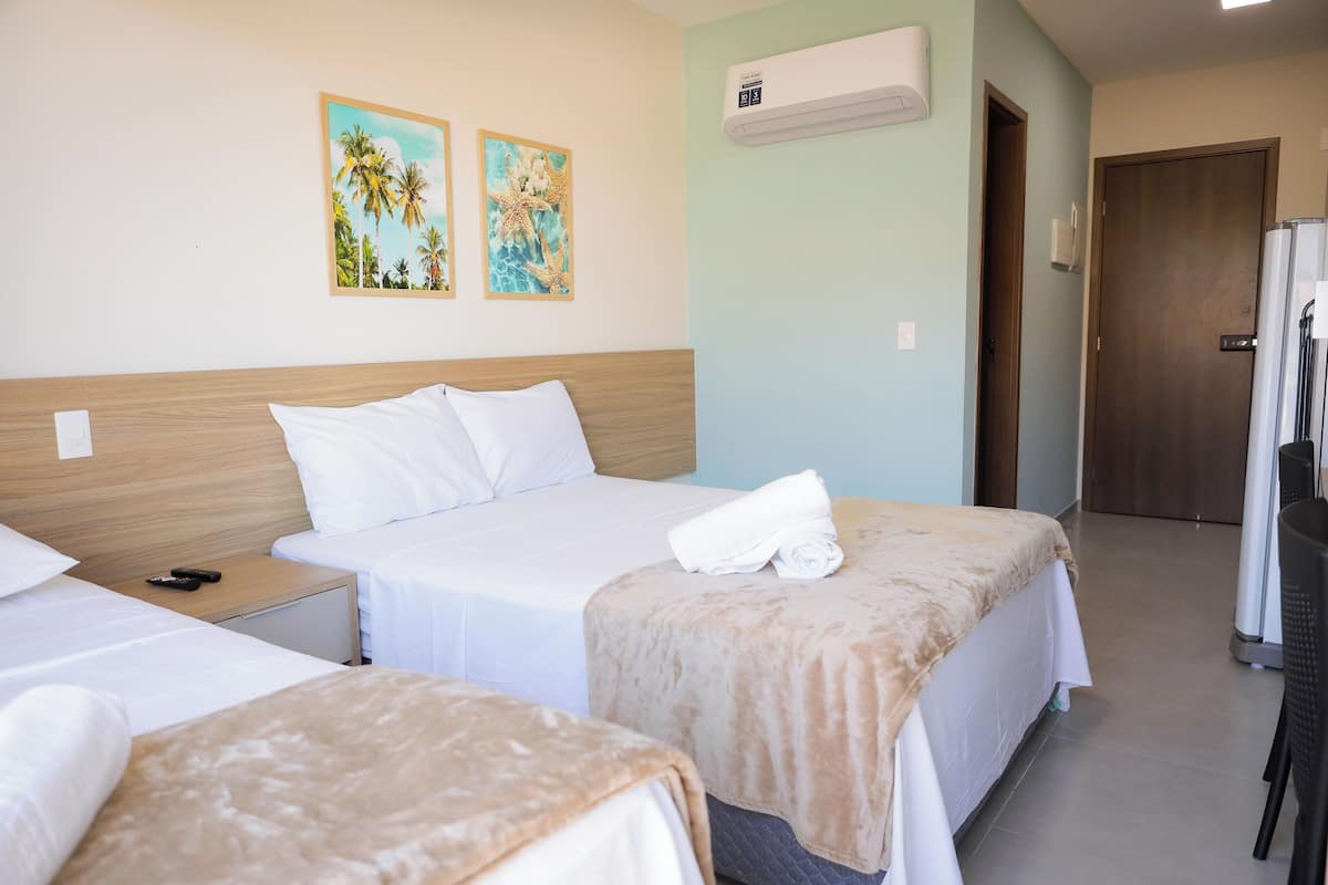 Habitación de hotel con dos camas, cabecero de madera, ropa de cama blanca y dos obras de arte en la pared.