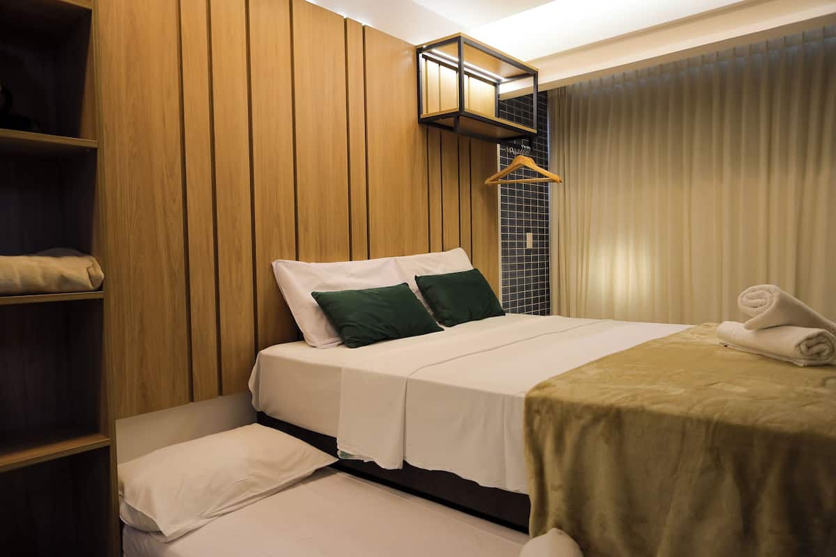 Una habitación de hotel con cama, una banca, un armario y una lámpara colgante.