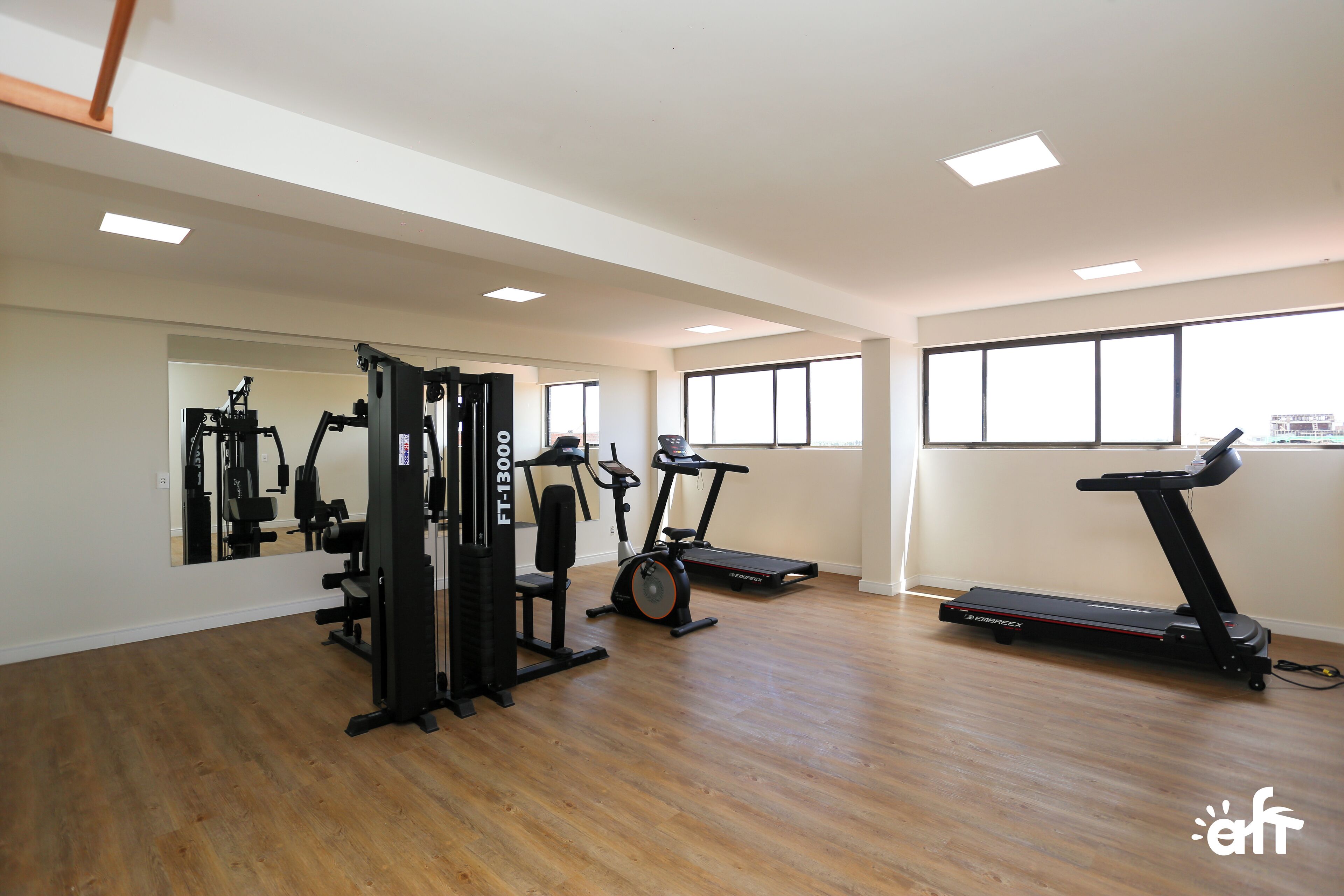 Ein großzügiger Fitnessraum mit Laufband, Crosstrainer und Kraftmaschine.