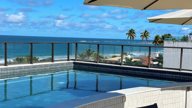 Uma piscina com vista para o oceano e palmeiras.