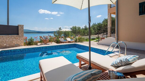Un espace aménagé au bord de la piscine, avec des chaises longues, une piscine et une vue sur la mer.
