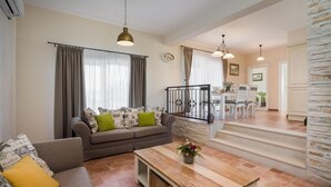 Un salon comprenant un canapé, une table basse et un escalier menant à une salle à manger.