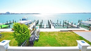 A marina with boats docked, a grassy area, and a view of the water. - Village West 1-Baywater 28th St, Free WiFi, W/D, AC (Ocean City)