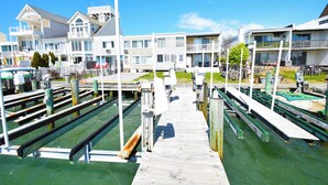 A marina with docked boats, a wooden pier, and white buildings with balconies. - Village West 1-Baywater 28th St, Free WiFi, W/D, AC (Ocean City)