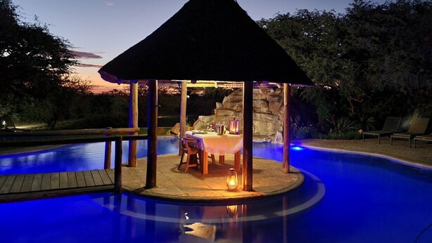 A gazebo with a table and chairs, surrounded by a swimming pool. - Mattanu Private Game Reserve (Dikgatlong)